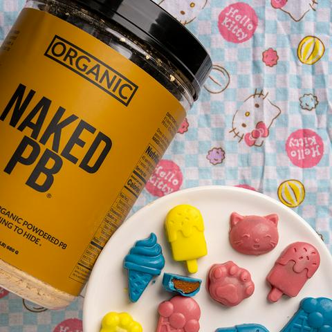 jar of organic peanut butter powder next to a plate of colorful peanut butter cups.