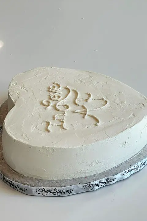 piping an anniversary message on the heart cake.