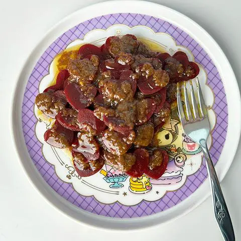 Top view of a beet salad with dressing where the beets are all heart shaped bites.