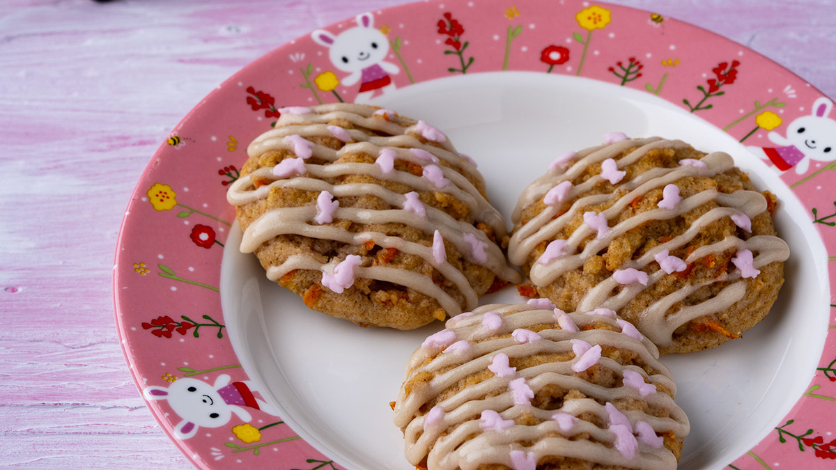 3 carrot cake cookies with cream cheese icing drizzle and pink bunny sprinkles.