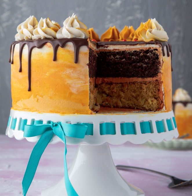 vegan chocolate orange cake on a cake stand with a slice missing
