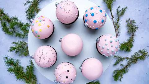 8 pastel pink vegan christmas cupcakes on a cake stand.