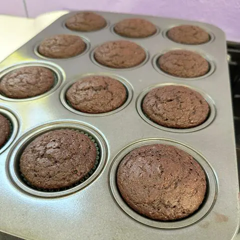 a cupcake pan filled with baked vegan chocolate cupcakes.