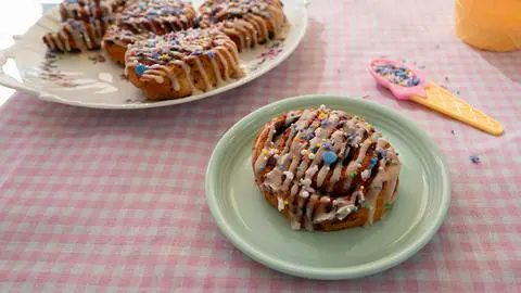 a single cinnamon roll on a small seafoam green plate.
