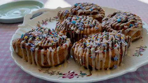 vegan cinnamon rolls with icing and sprinkles on a plate.