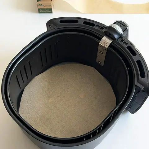 air fryer basket with parchment paper in the bottom.