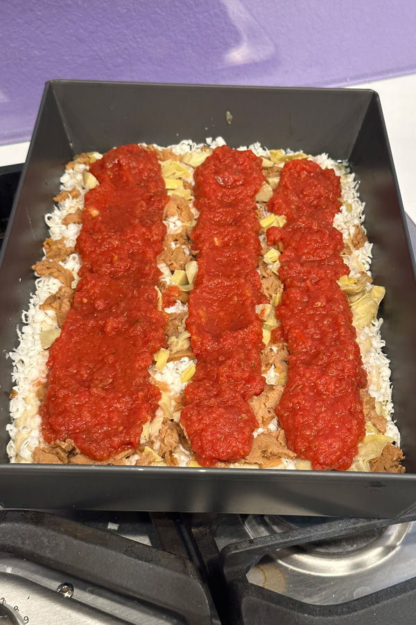 adding 3 rows of pizza sauce to the vegan detroit style pizza