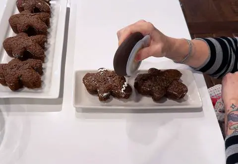 decorating vegan gingerbread cake people with white frosting.