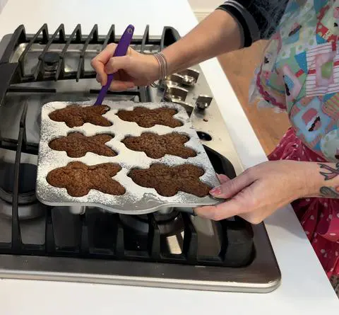 using a small purple baking spatula to scoop the gingerbread cake out of the pan.