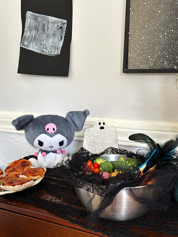 a table with random Halloween decorations and mini vegan pizzas.