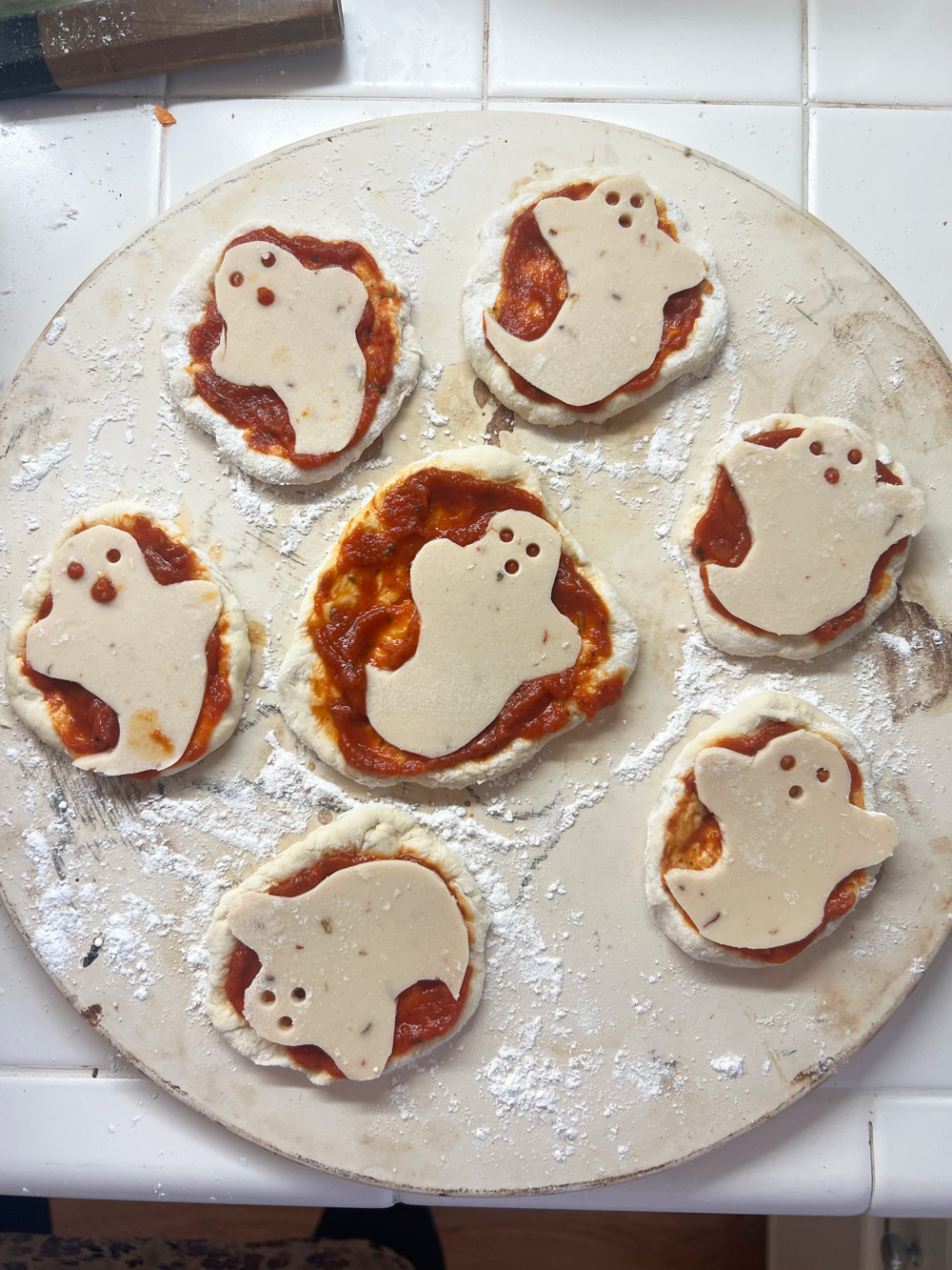 mini ghost pizzas on a baking stone.