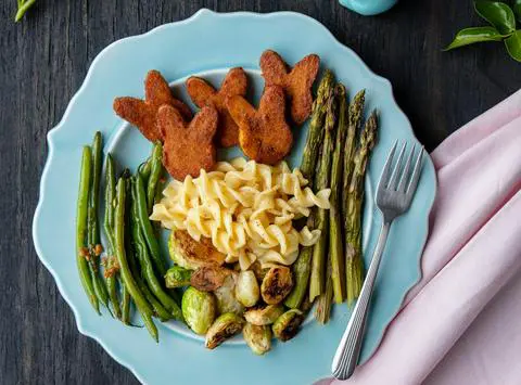 bunny-shaped vegan ham on a plate with veggies and mac n cheese.