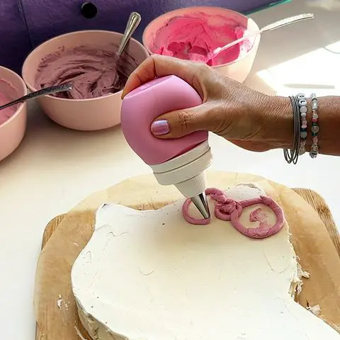 drawing the shape of hello kitty’s bow using a frosting bulb.