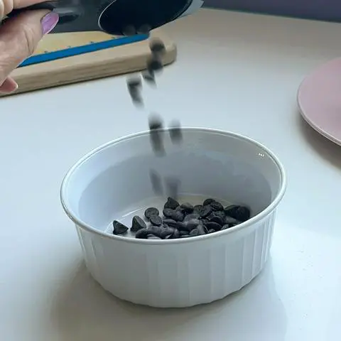 pouring vegan chocolate chips into a microwave safe bowl.