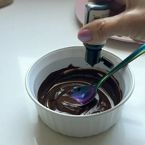 adding black food coloring to the vegan melted chocolate.