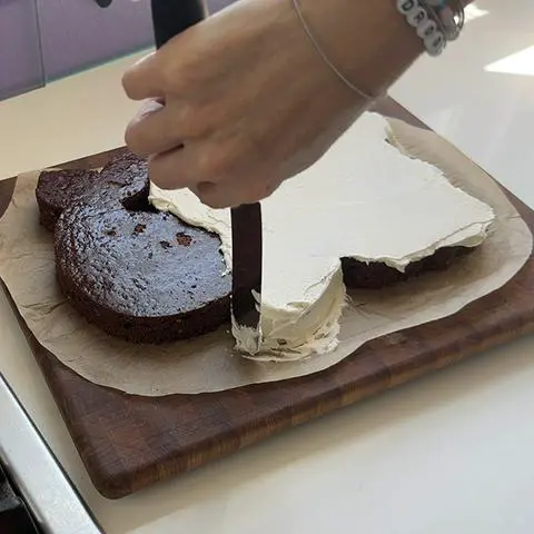 smoothing vegan buttercream frosting on the side of the cake.
