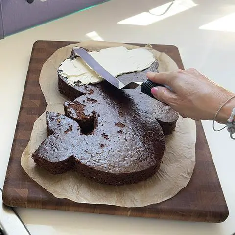 smoothing vegan buttercream frosting on hello kitty’s head.