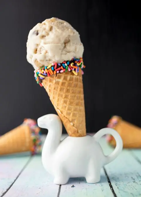 cookie dough ice cream in a sugar cone with vegan rainbow sprinkles.