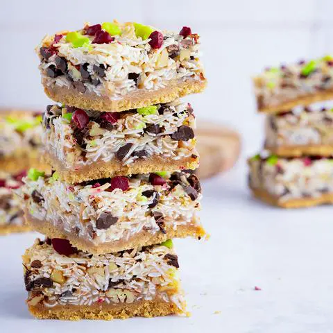 a stack of 4 vegan magic bars, with more bars scattered around.