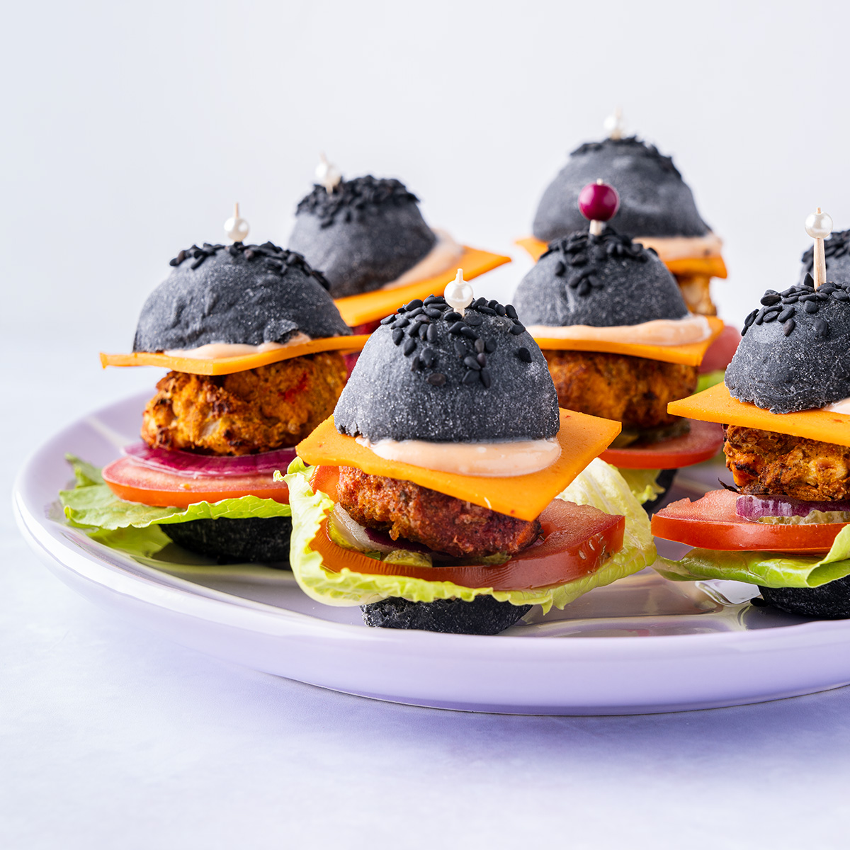 vegan mini burgers on black buns.