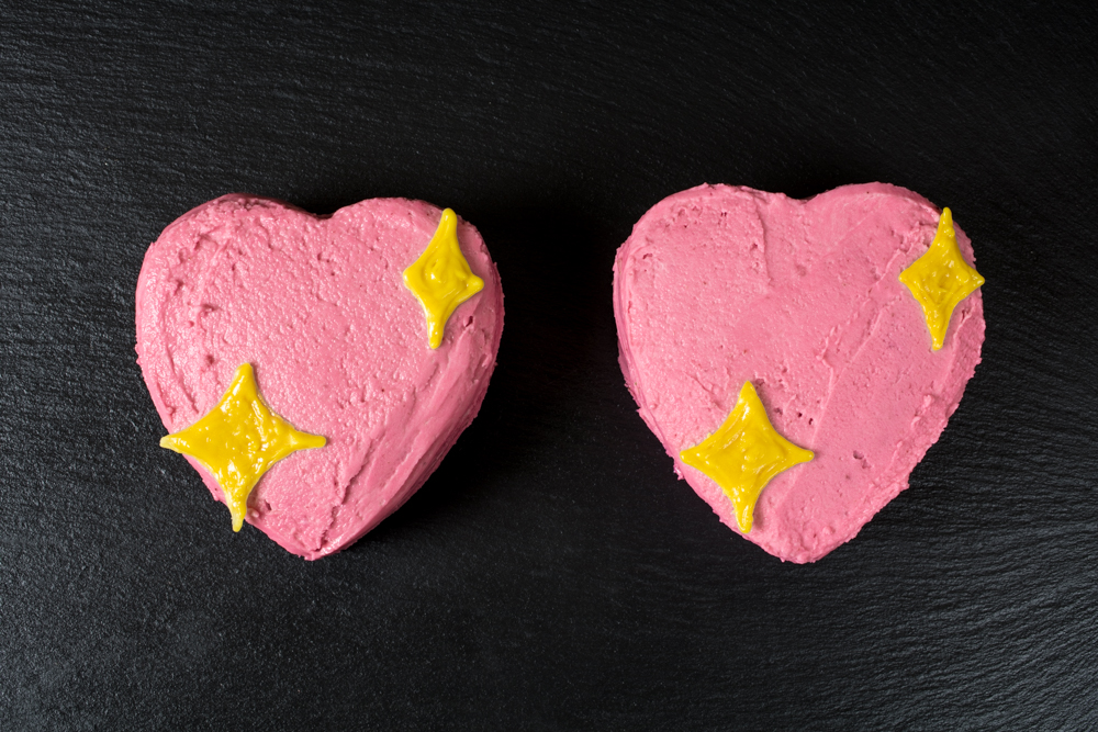 2 vegan mini cakes that are decorated to look like the sparkle heart emoji
