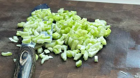 diced celery on a cutting board with a knife.