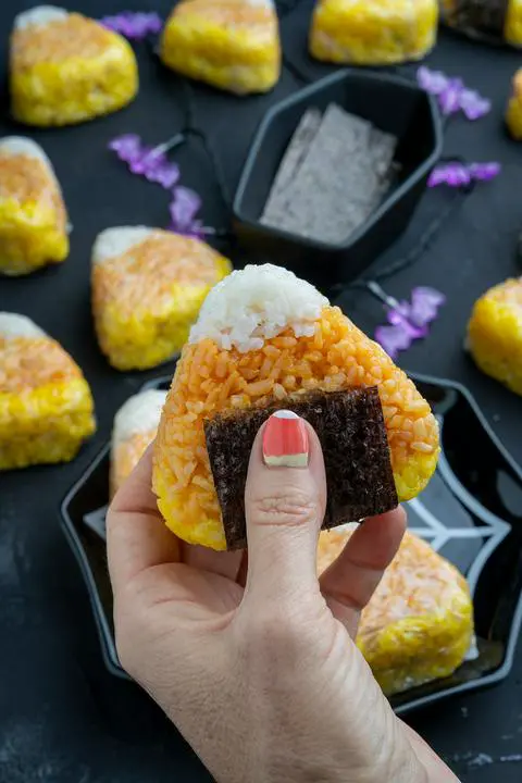 holding a vegan tuna onigiri with matching nail polish.