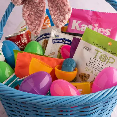 a peanut butter cup in a plastic easter egg inside of an easter basket.