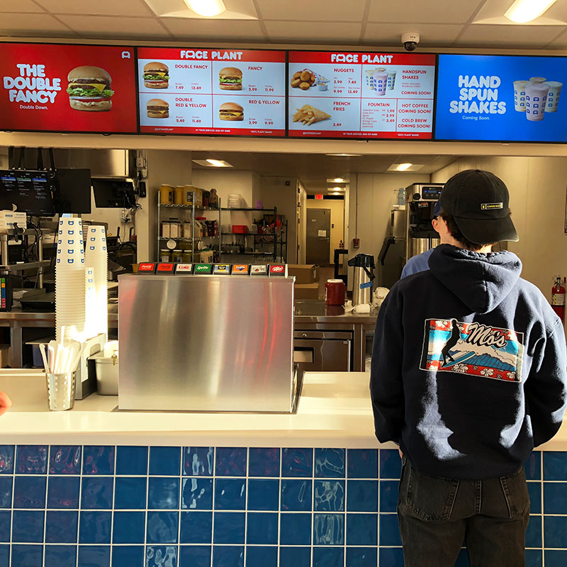 someone ordering at the counter with the menu in the background.