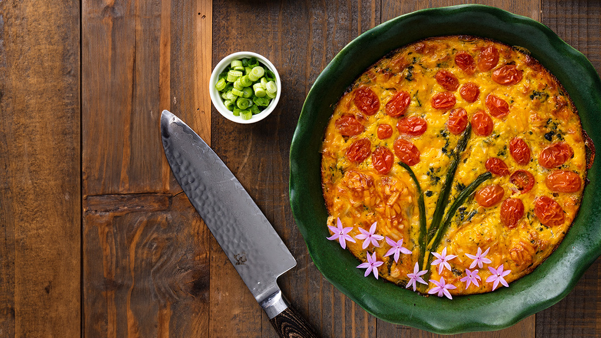 a wood table with a spring decorated quiche on the right.
