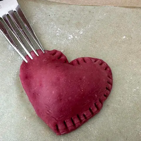 crimping the edges of each ravioli with a fork