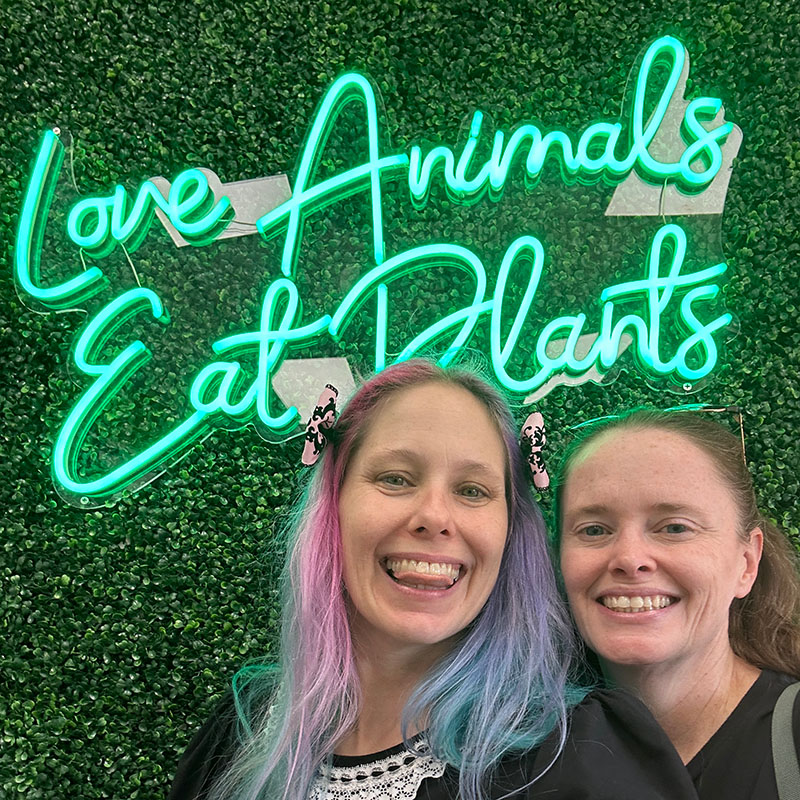 me and Crystal under the neon sign at San Diego Vegan Market in San Diego.
