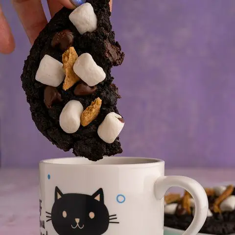 about to dunk half a chocolate s’mores cookie into coffee.