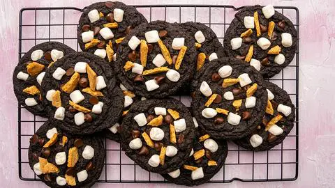 chocolate s’mores cookies on a cooling rack on a pink table.