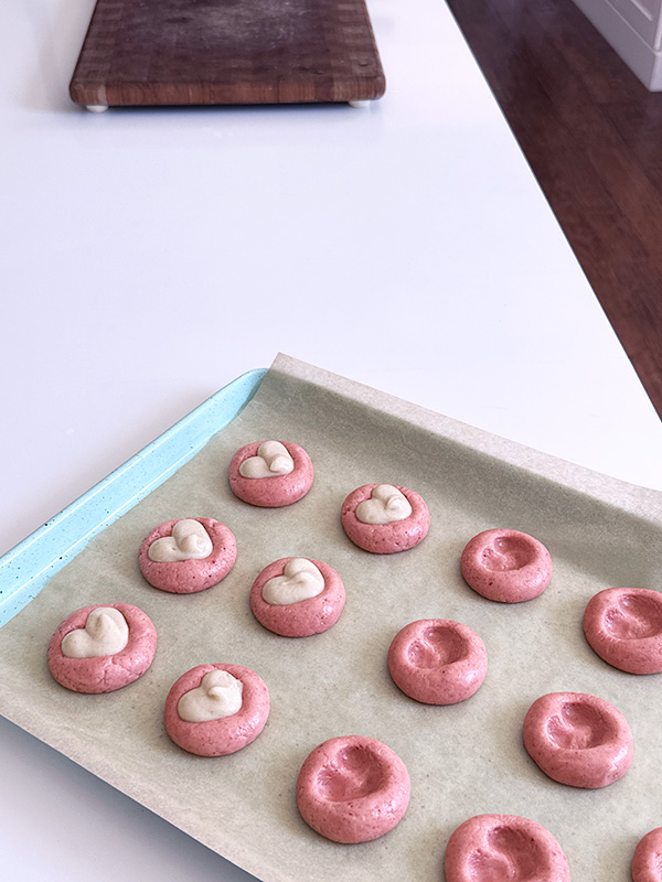 filling the strawberry thumbprint cookies with vegan cheesecake filling