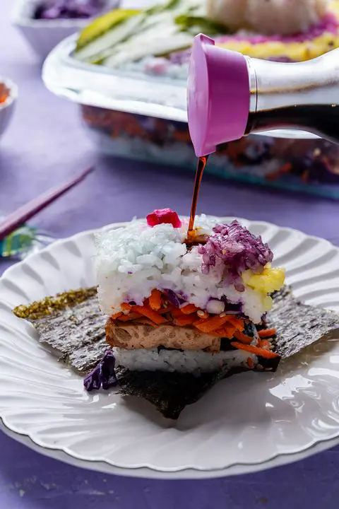 drizzling soy sauce onto a piece of sushi casserole