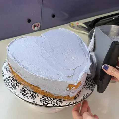 smoothing the frosting on the sides of the cake.