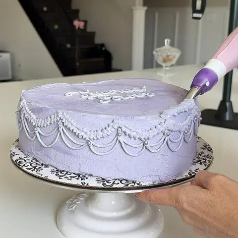 piping the ruffle border on the top of the cake.