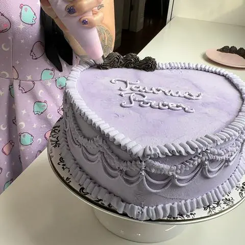 piping a black shell border on top of the cake.