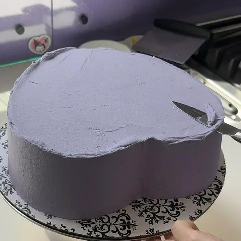 using a knife to cut off the overhang of frosting.