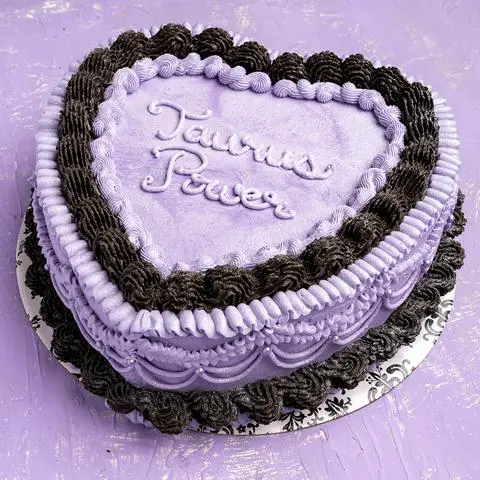 a lavender and black heart shaped vegan cake decorated with a lambeth vintage style.